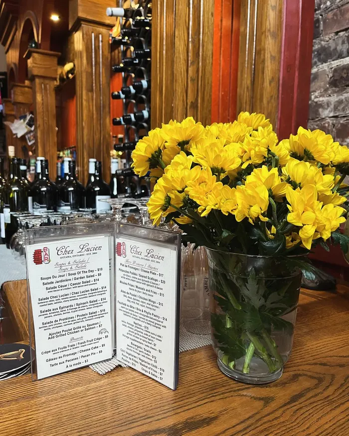 Chez Lucien menu card and yellow flowers on the wooden bar