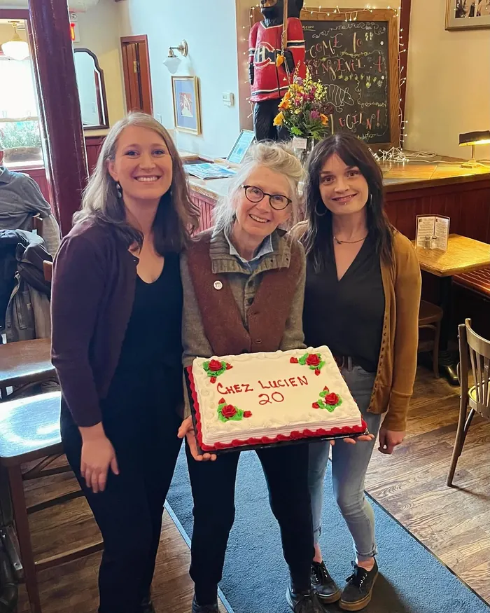 Three Chez Lucien staff holding a cake that reads Chez Lucien 20